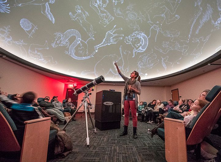 A woman gives a presentation in the planetarium auditorium.